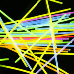 Image of vibrant stack of neon glow sticks scattered over black background. Light and colour concept.